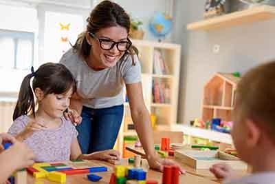 Preschool teacher with children playing with colorful wooden did